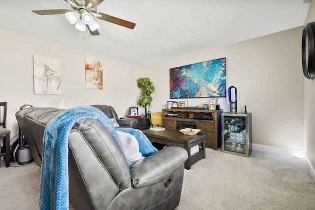 living area with a ceiling fan, baseboards, and light carpet