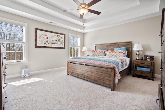 carpeted bedroom with visible vents, a ceiling fan, a raised ceiling, and baseboards