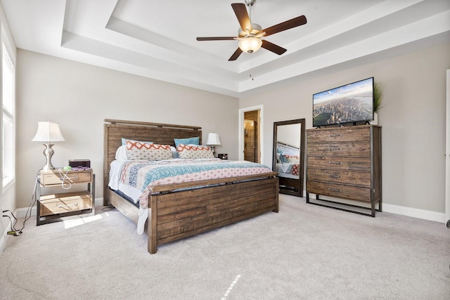 carpeted bedroom featuring ceiling fan, a raised ceiling, and baseboards