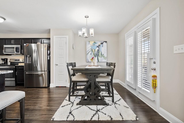 dining area with dark wood-type flooring, a notable chandelier, and baseboards