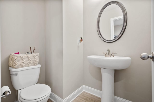 bathroom featuring toilet, wood finished floors, and baseboards