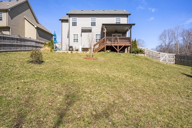 back of house featuring a ceiling fan, a deck, a lawn, and a fenced backyard