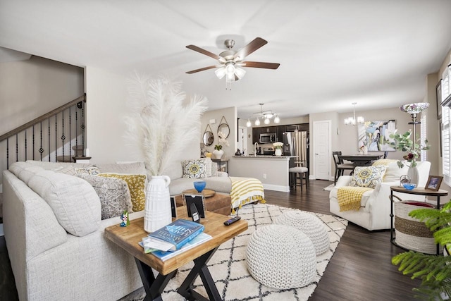 living room with dark wood finished floors, stairs, and ceiling fan with notable chandelier