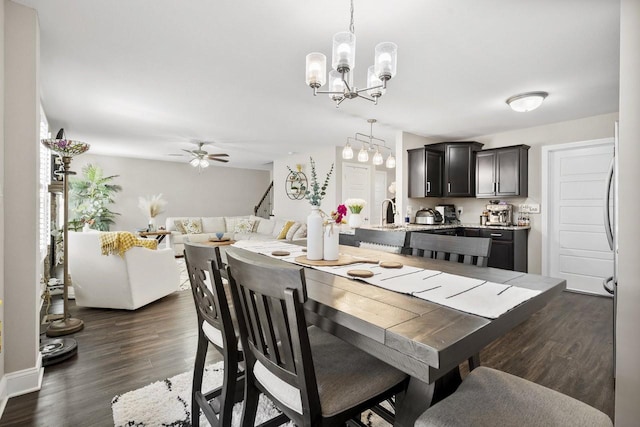 dining area with dark wood-style floors, ceiling fan with notable chandelier, and stairs