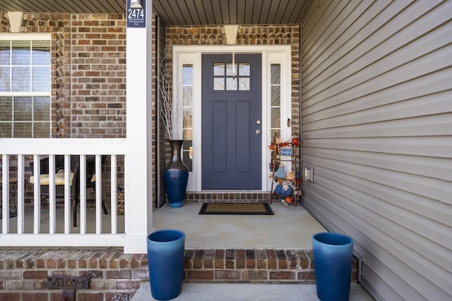 property entrance with brick siding and a porch