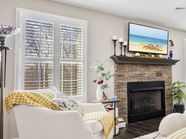 interior space with a stone fireplace, visible vents, a healthy amount of sunlight, and wood finished floors