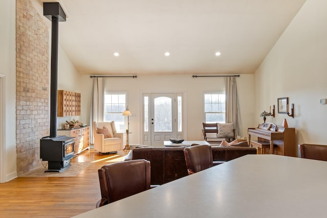 living area with a wealth of natural light, light wood-type flooring, a wood stove, and recessed lighting