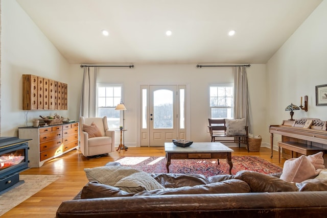 living room featuring a wood stove, light wood finished floors, vaulted ceiling, and recessed lighting