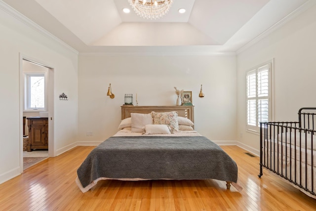 bedroom featuring light wood finished floors, baseboards, a raised ceiling, and a notable chandelier