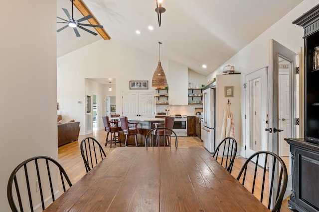 dining area featuring ceiling fan, high vaulted ceiling, light wood-type flooring, and baseboards