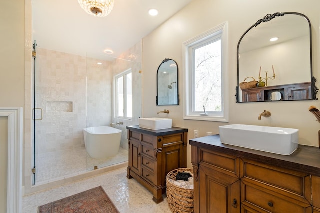 bathroom featuring a stall shower, a freestanding bath, two vanities, and a sink