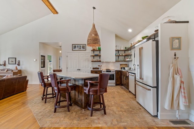 kitchen with white appliances, a kitchen island, light countertops, decorative backsplash, and open shelves