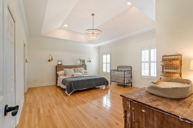 bedroom with a tray ceiling, recessed lighting, an inviting chandelier, light wood-style floors, and baseboards