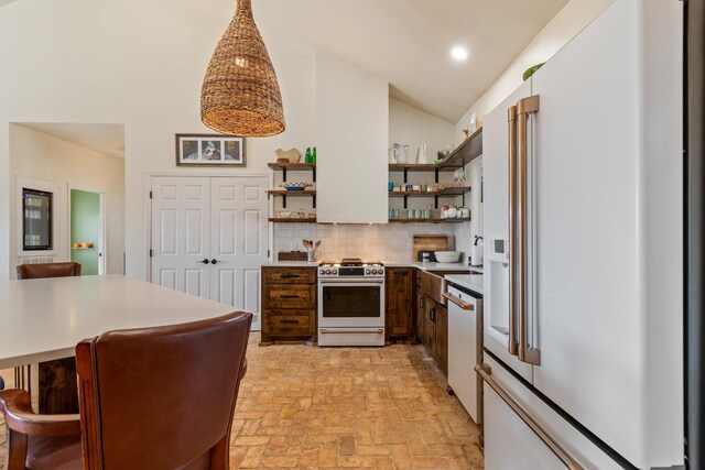 kitchen featuring tasteful backsplash, high end appliances, brick floor, light countertops, and open shelves