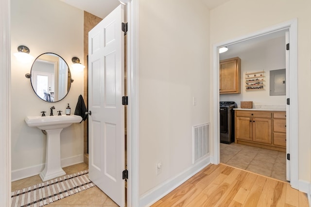 bathroom featuring electric panel, visible vents, baseboards, and wood finished floors