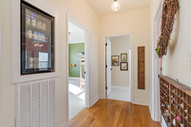 hallway with light wood-type flooring, baseboards, and visible vents