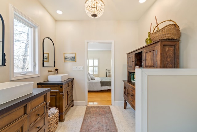 bathroom with plenty of natural light, two vanities, a sink, and ensuite bathroom