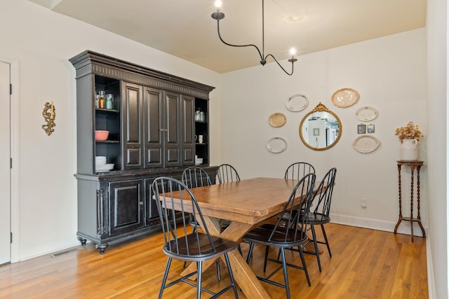 dining area featuring visible vents, light wood-style flooring, and baseboards