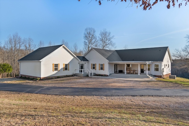 exterior space featuring covered porch, metal roof, and driveway