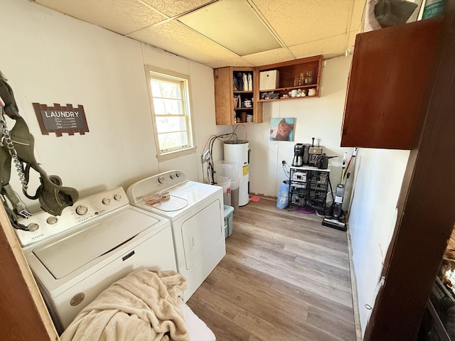 laundry room with water heater, cabinet space, washer and clothes dryer, and light wood finished floors