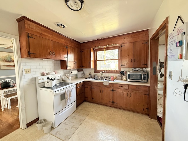 kitchen featuring stainless steel microwave, electric range, visible vents, light countertops, and brown cabinetry