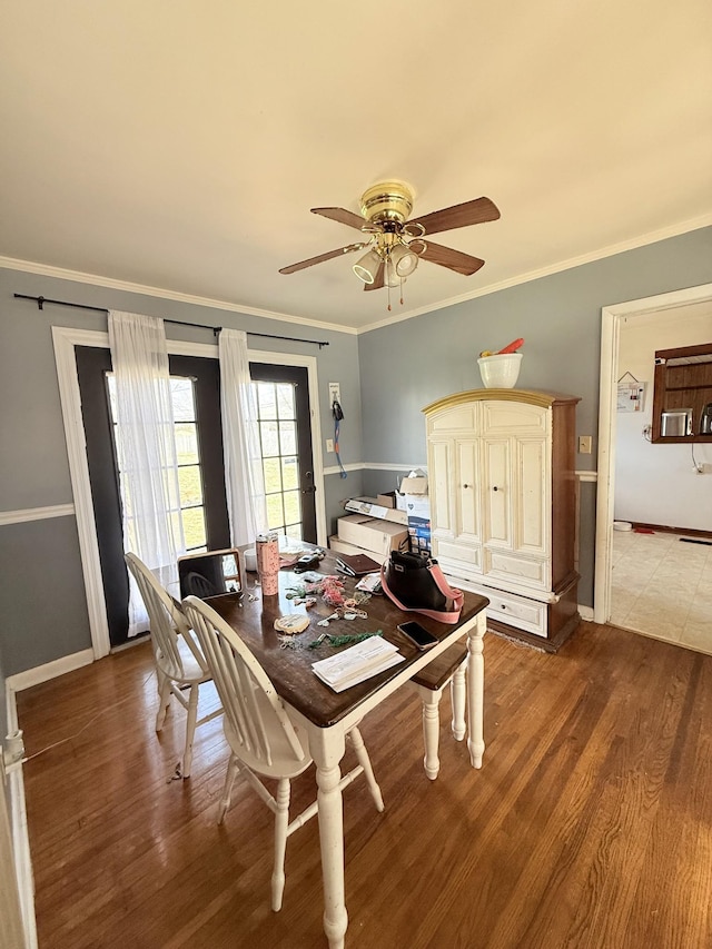 dining area featuring crown molding, baseboards, and wood finished floors