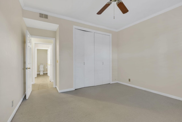 unfurnished bedroom with visible vents, baseboards, crown molding, carpet flooring, and a closet