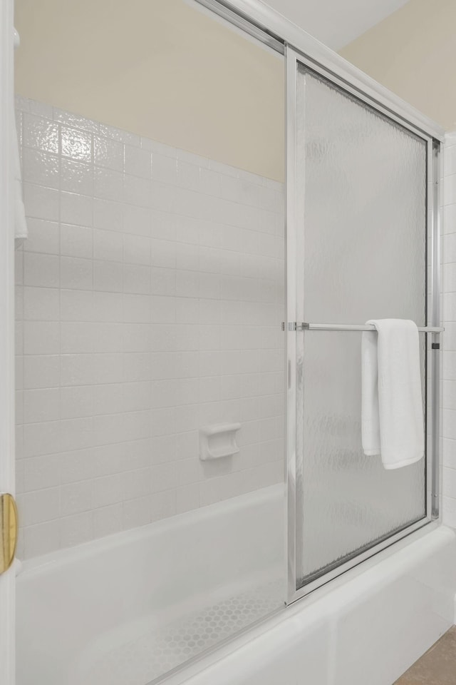 bathroom featuring combined bath / shower with glass door