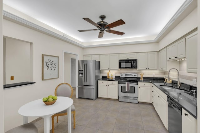 kitchen with a tray ceiling, tasteful backsplash, a sink, ceiling fan, and black appliances