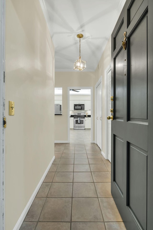 corridor featuring ornamental molding, a notable chandelier, baseboards, and light tile patterned floors