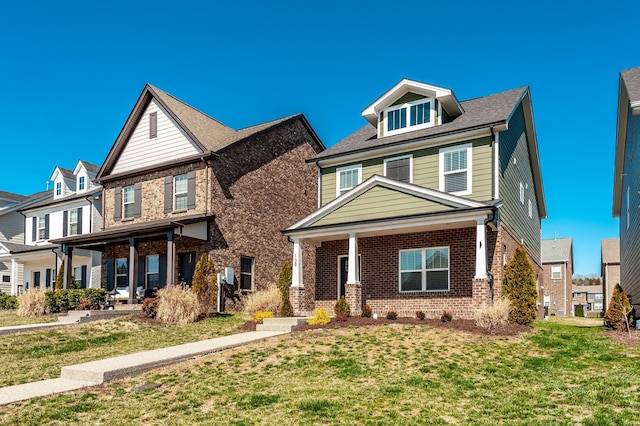 view of front of property featuring brick siding, covered porch, and a front yard