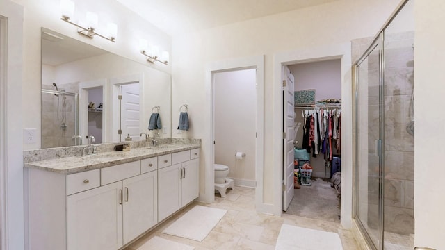 bathroom with a walk in closet, a sink, a shower stall, and toilet