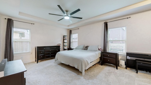 bedroom featuring carpet floors, a raised ceiling, visible vents, and a ceiling fan