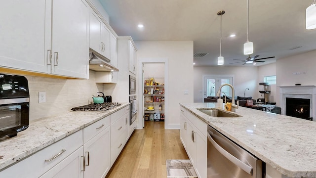 kitchen featuring under cabinet range hood, a sink, visible vents, light wood-style floors, and appliances with stainless steel finishes