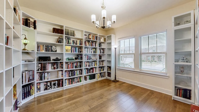 sitting room featuring wood-type flooring, baseboards, and an inviting chandelier