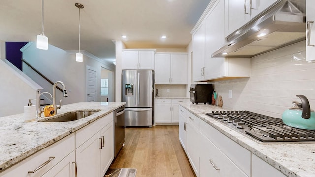 kitchen with light wood-style flooring, stainless steel appliances, under cabinet range hood, white cabinetry, and a sink