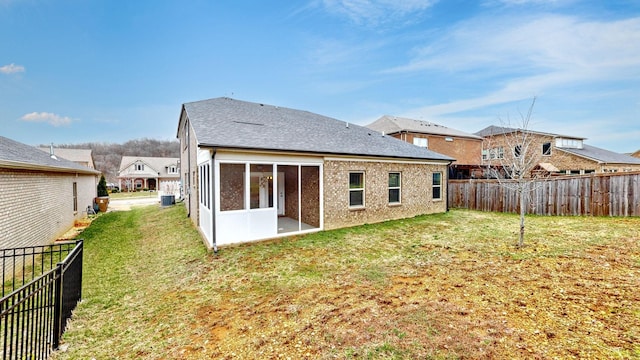 back of house with a sunroom, a fenced backyard, a lawn, and roof with shingles