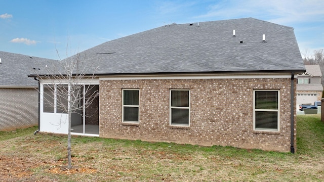 rear view of house with roof with shingles, brick siding, and a lawn