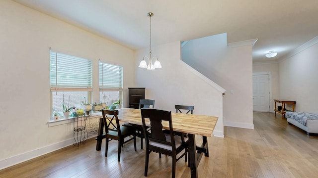 dining room with a chandelier, baseboards, crown molding, and light wood finished floors