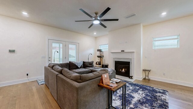 living room featuring light wood finished floors, a high end fireplace, visible vents, and a healthy amount of sunlight