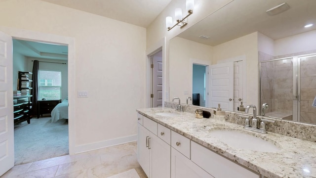 ensuite bathroom with a sink, a shower stall, baseboards, and double vanity