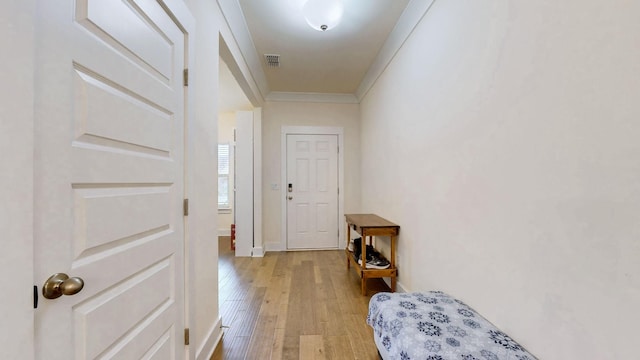 entryway with baseboards, visible vents, crown molding, and light wood finished floors