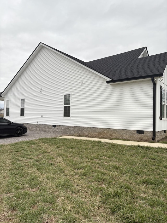 view of side of property with a yard, crawl space, and roof with shingles