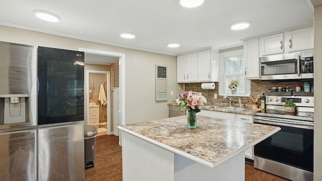 kitchen featuring stainless steel appliances, a sink, white cabinetry, backsplash, and dark wood-style floors