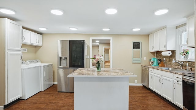 kitchen with dark wood-type flooring, a center island, independent washer and dryer, stainless steel appliances, and a sink