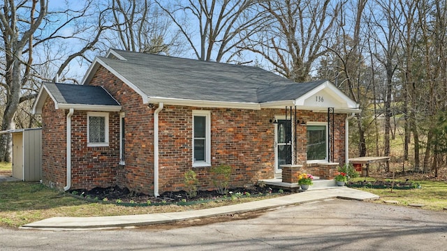 view of property exterior with a shingled roof and brick siding