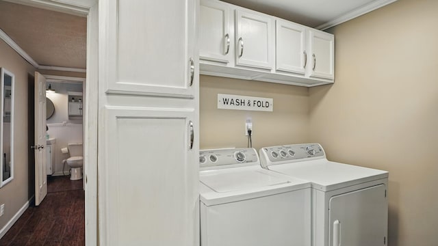 laundry room featuring dark wood finished floors, washer and clothes dryer, cabinet space, ornamental molding, and baseboards