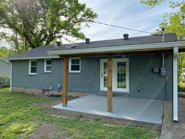 rear view of house with crawl space, a patio area, a lawn, and brick siding