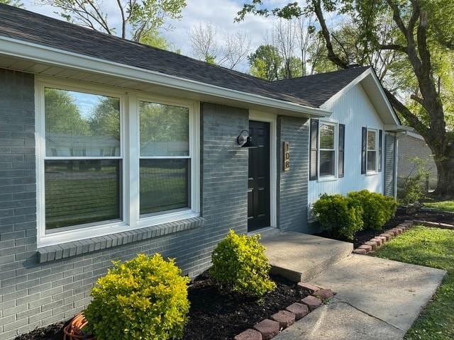 view of front of house with a shingled roof and brick siding