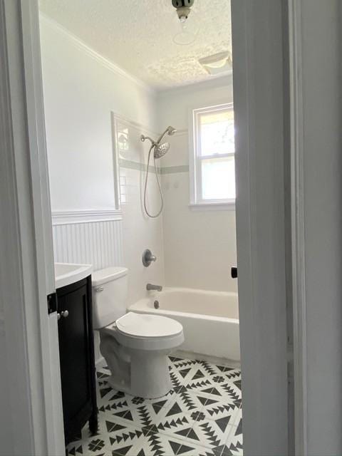 bathroom with wainscoting, toilet, bathtub / shower combination, a textured ceiling, and vanity